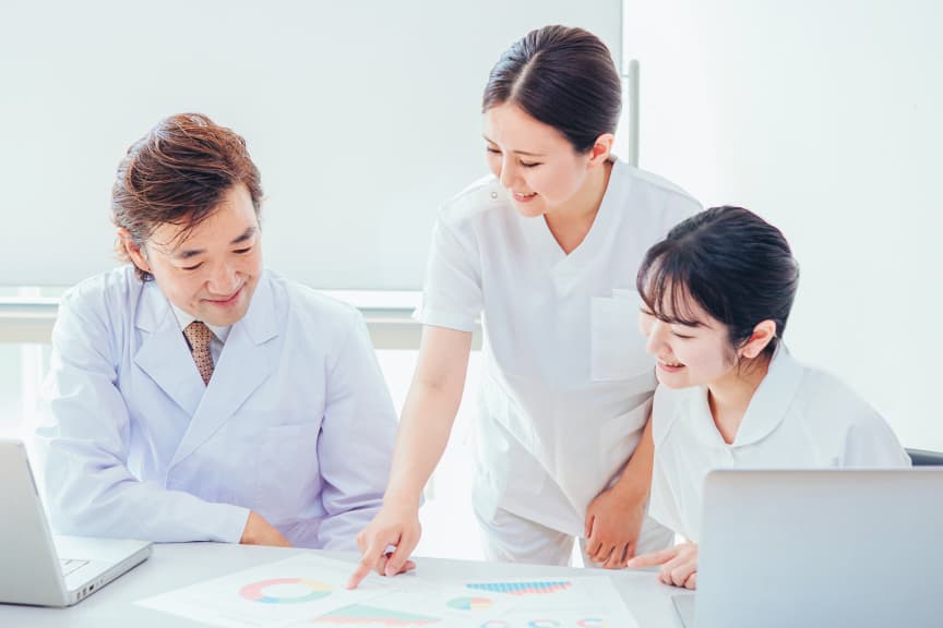 看護教員と学生が資料を見ながら話し合う様子。チームで学ぶ看護の授業風景