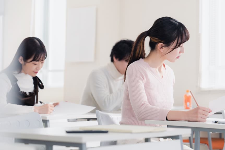 教室で真剣に筆記試験を受ける学生たちの様子