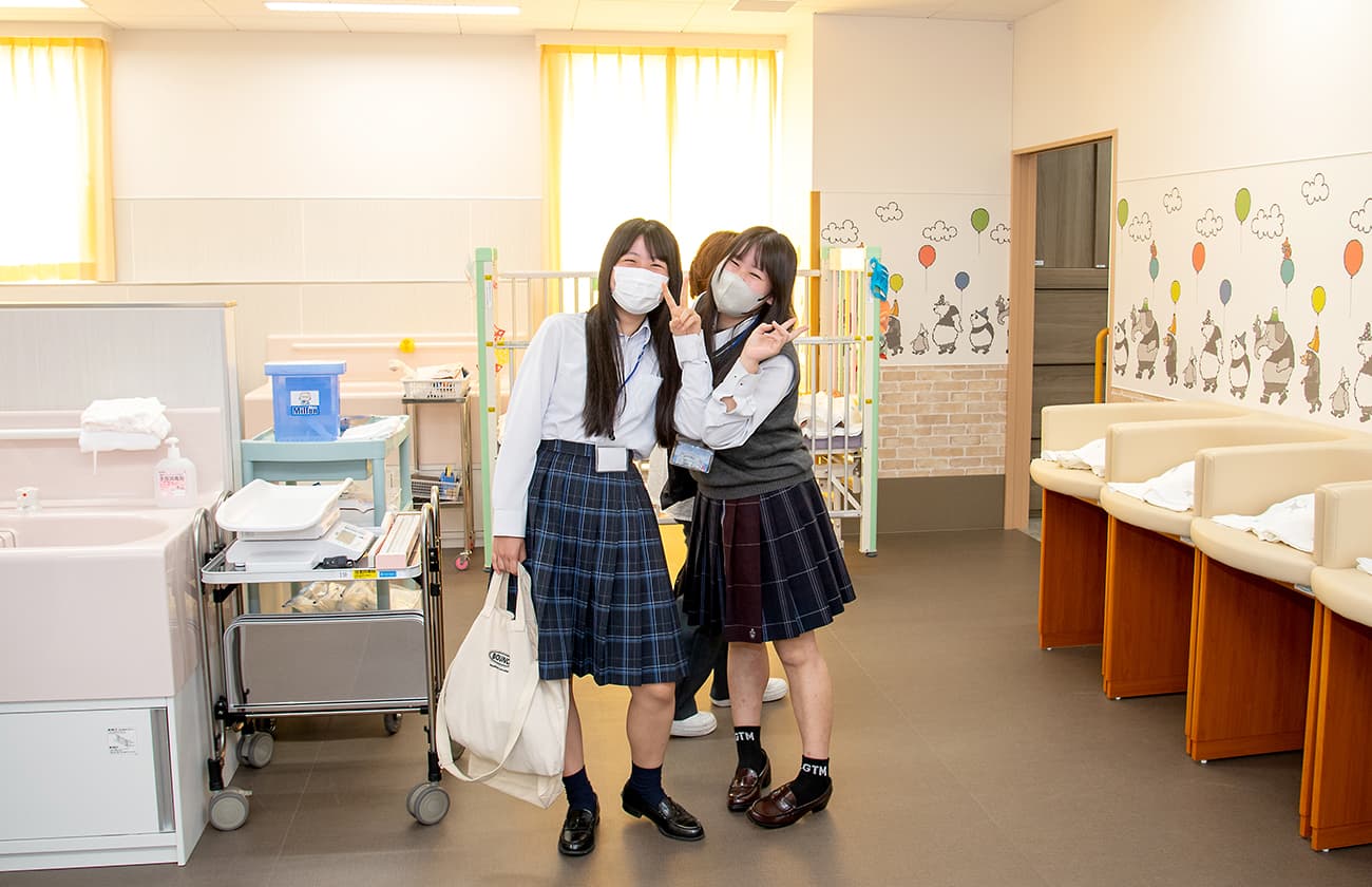 実習室で制服姿の学生2人が笑顔でピースサインをしている様子